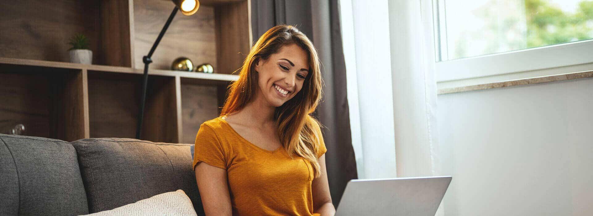 A woman smiling while using a laptop